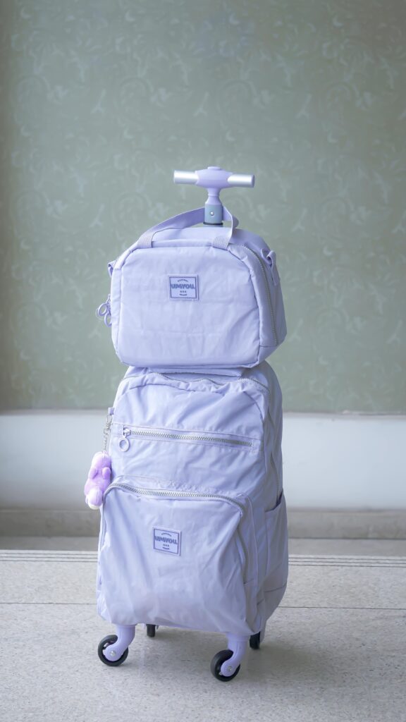 Stylish pastel purple luggage set against a minimalist light green wall indoors.