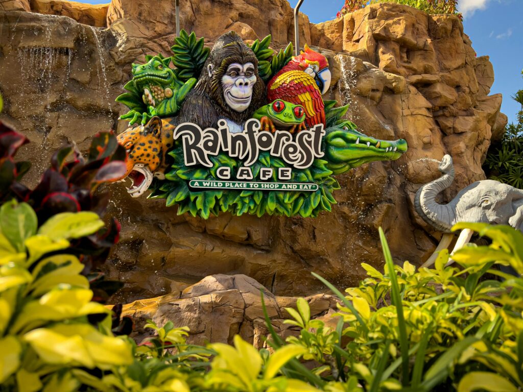 Vibrant Rainforest Cafe sign surrounded by lush greenery and animal sculptures in Lake Buena Vista.