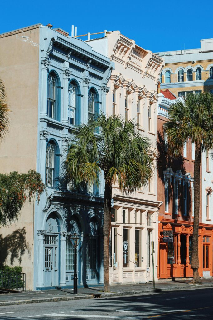 Vibrant historic townhouses with palm trees on a sunny street in Charleston, SC.