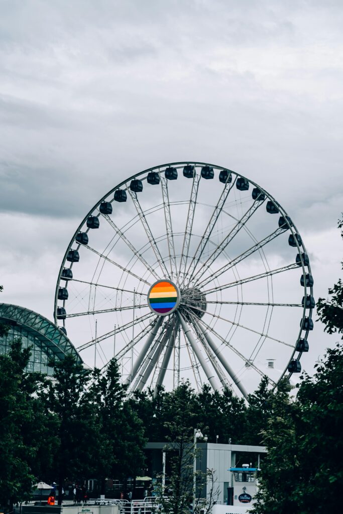 Modern ferris wheel in Chicago with a rainbow hub, amidst cloudy skies.