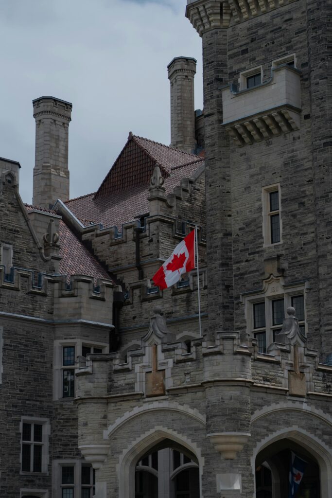 Historic stone castle featuring Canadian flag in daytime.
