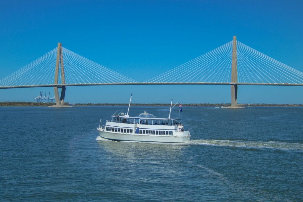 White ferry boat sails near Arthur Ravenel Jr. Bridge in Charleston.